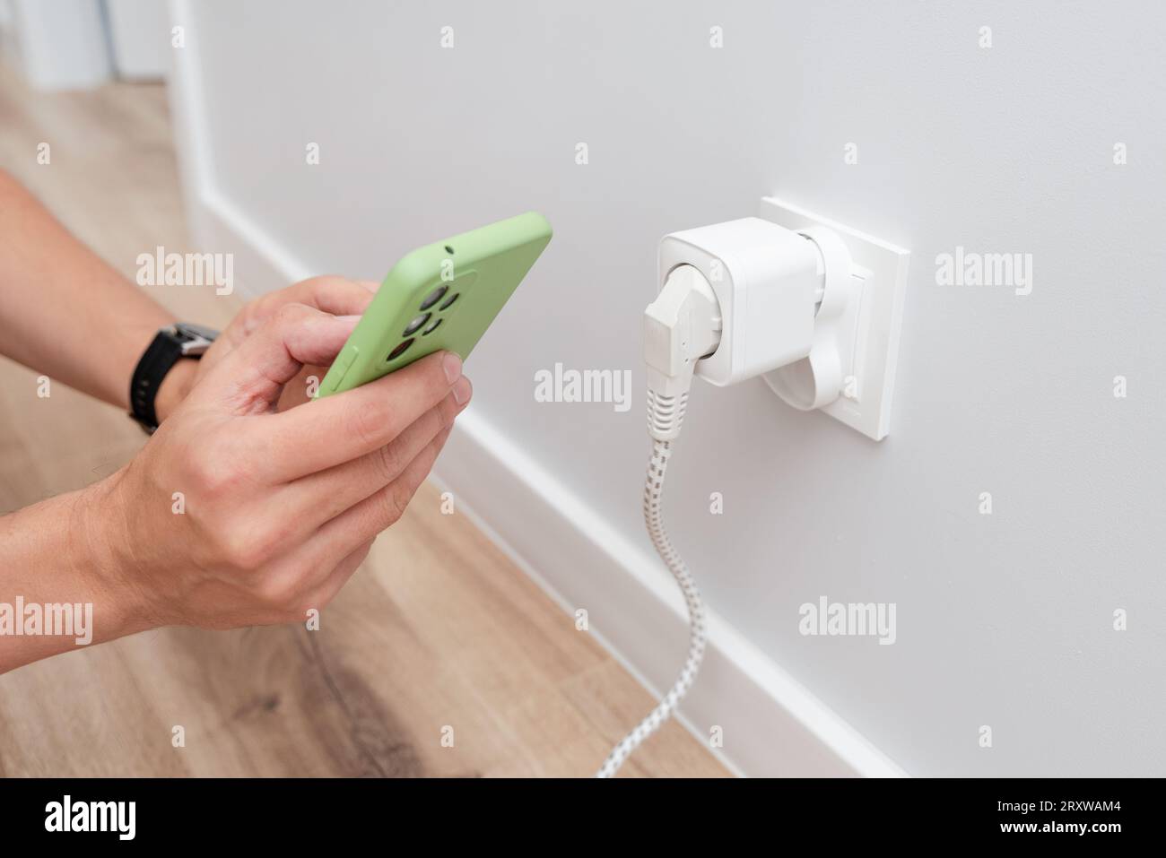 Verwenden Sie die Wi-fi Smart-Steckdose an der Wand in einem intelligenten Zuhause, um den Stromverbrauch zu steuern Stockfoto