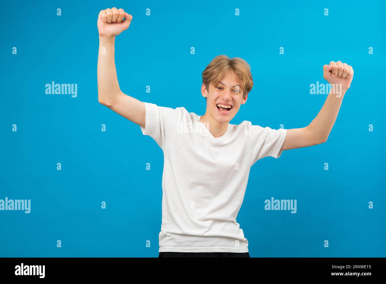 Extrem aufgeregt überglücklich Teenager-Junge schrie ja Geste, erstaunt über seinen Sieg, Triumph. Innenaufnahme des Studios isoliert auf blauem Hintergrund Stockfoto