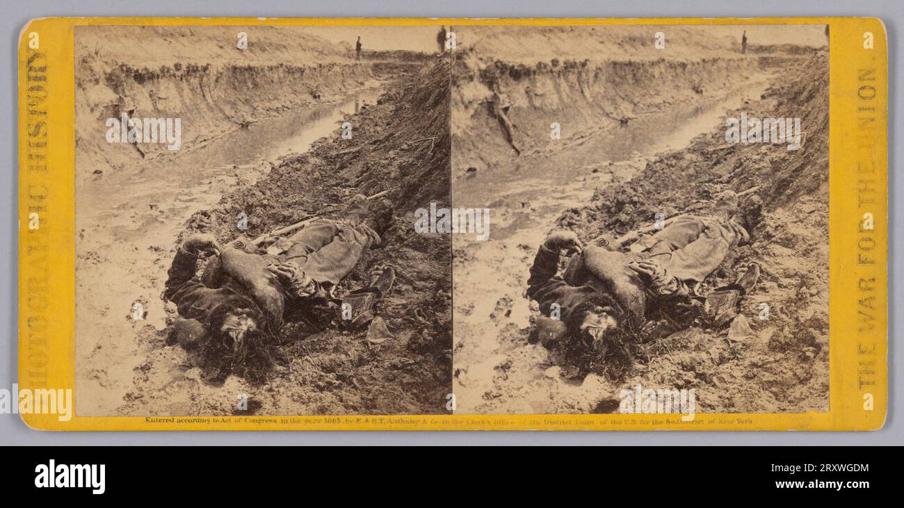 Dieser Stereograph mit Albumdruck zeigt den Körper eines nicht identifizierten verstorbenen Soldaten der Konföderierten Staaten von Amerika, der in einem schlammigen Graben liegt, wobei sein Kopf der Kamera am nächsten liegt. Zwei Personen stehen über dem Graben im Hintergrund und sind außerhalb des Kamerafokus. Der Albumdruck ist auf gelbem Karton angebracht. Die Worte „FOTOGESCHICHTE“ sind vertikal entlang der linken Kante des Montieres gedruckt, während die Worte „KRIEG FÜR DIE UNION“ vertikal auf der rechten Seite gedruckt sind. Unter dem Foto steht der Text mit der Aufschrift „eingetragen nach dem Gesetz des Kongresses im Jahr 1865 von E. & H. T. an Stockfoto