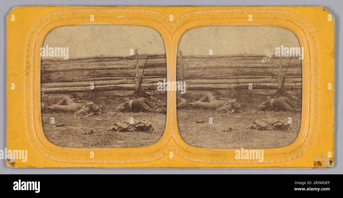 Dieser Stereograph mit Albumen-Druck zeigt die Leichen von zwei (2) verstorbenen konföderierten Soldaten, die vor einem Zaun auf dem Schlachtfeld von Antietam, Maryland, liegen. Im rechten Vordergrund liegt ein Kleidungsstück oder eine Decke. Der Druck ist auf gelbem Karton mit einem abgerundeten quadratischen Rahmen und einer zentralen Trennwand mit geprägtem Design montiert. Die Rückseite der Halterung ist leer. Stockfoto