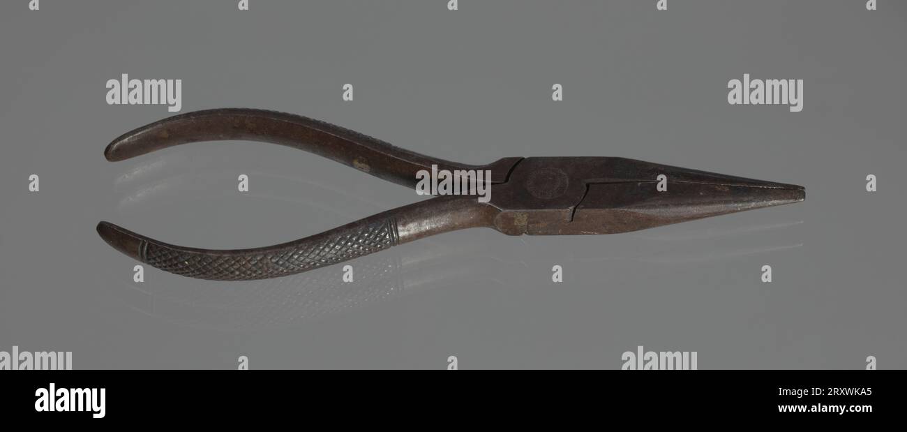 Diese Nadelzange wurde in der Werkstatt von C. Edgar Patience gefunden. Die Metallzange hat Gitterabschnitte an der Außenkante jedes Griffs zum Greifen. Auf einer Seite des Stifts ist Text mit der Aufschrift „REUMSHUSSELL / GERMANY“ eingeprägt. Stockfoto