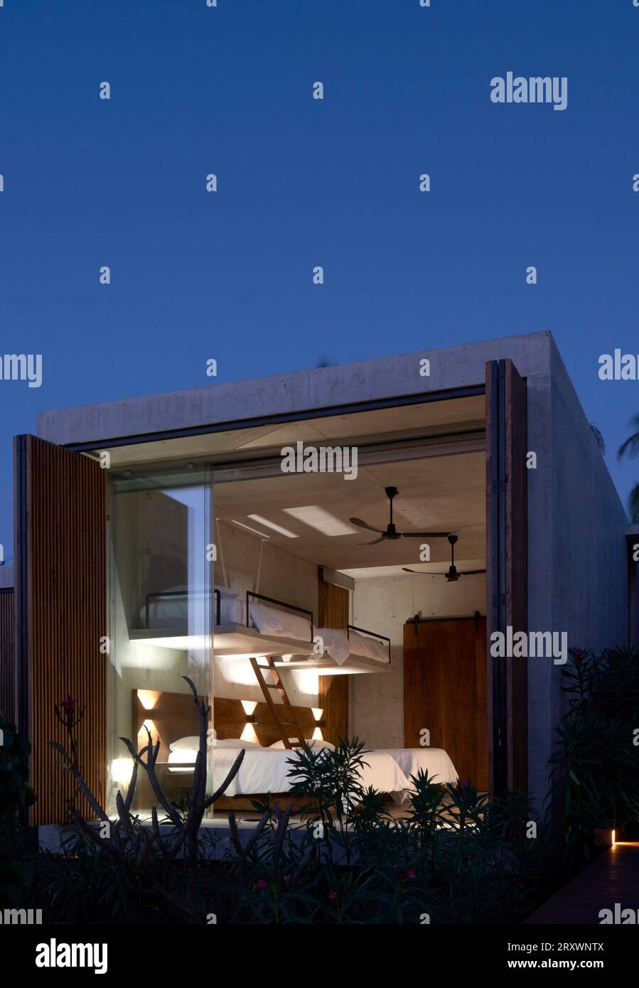 Beleuchteter Innenraum des Schlafzimmermoduls in der Abenddämmerung. Casa Leria, Puerto Escindido, Mexiko. Architekt: TAC Taller Alberto Calleja, 2023. Stockfoto