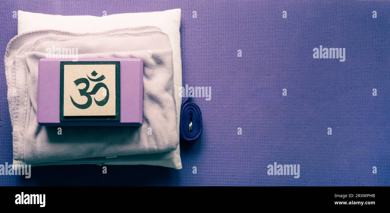 Blick auf Yoga-Ausrüstung aus einem hohen Winkel. Yogamatte, Block, Gurt, Decke und Kissen. OM-Zeichen. Leerzeichen kopieren Stockfoto