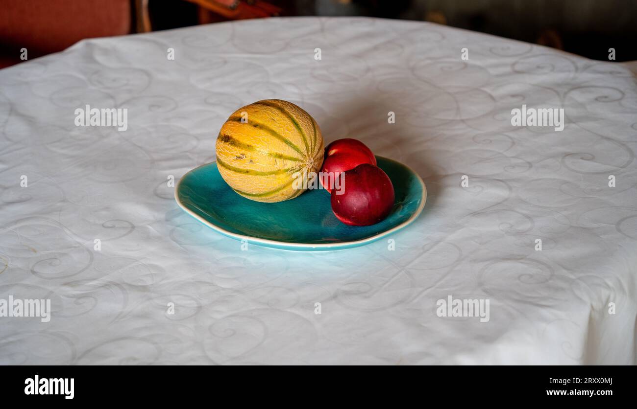 Stillleben mit Melone und Pfirsichen auf blauem Teller Stockfoto