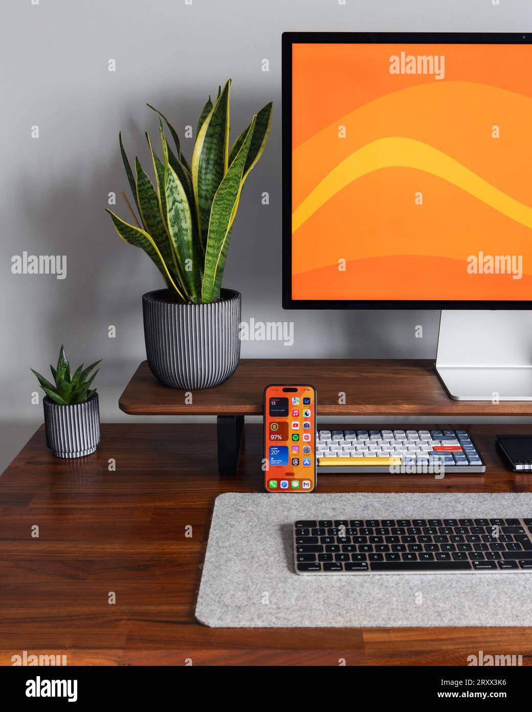 LONDON - 26. SEPTEMBER 2023: Apple Studio Display und Mac Mini Computer im modernen Home Office, Arbeit von zu Hause minimaler Schreibtisch mit Schlangenpflanze Stockfoto