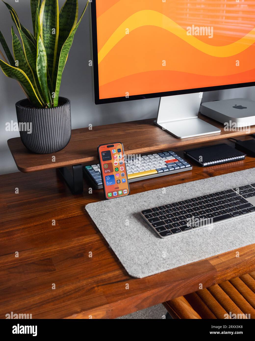 LONDON - 26. SEPTEMBER 2023: Apple Studio Display und Mac Mini Computer im modernen Home Office, Arbeit von zu Hause minimaler Schreibtisch mit Schlangenpflanze Stockfoto