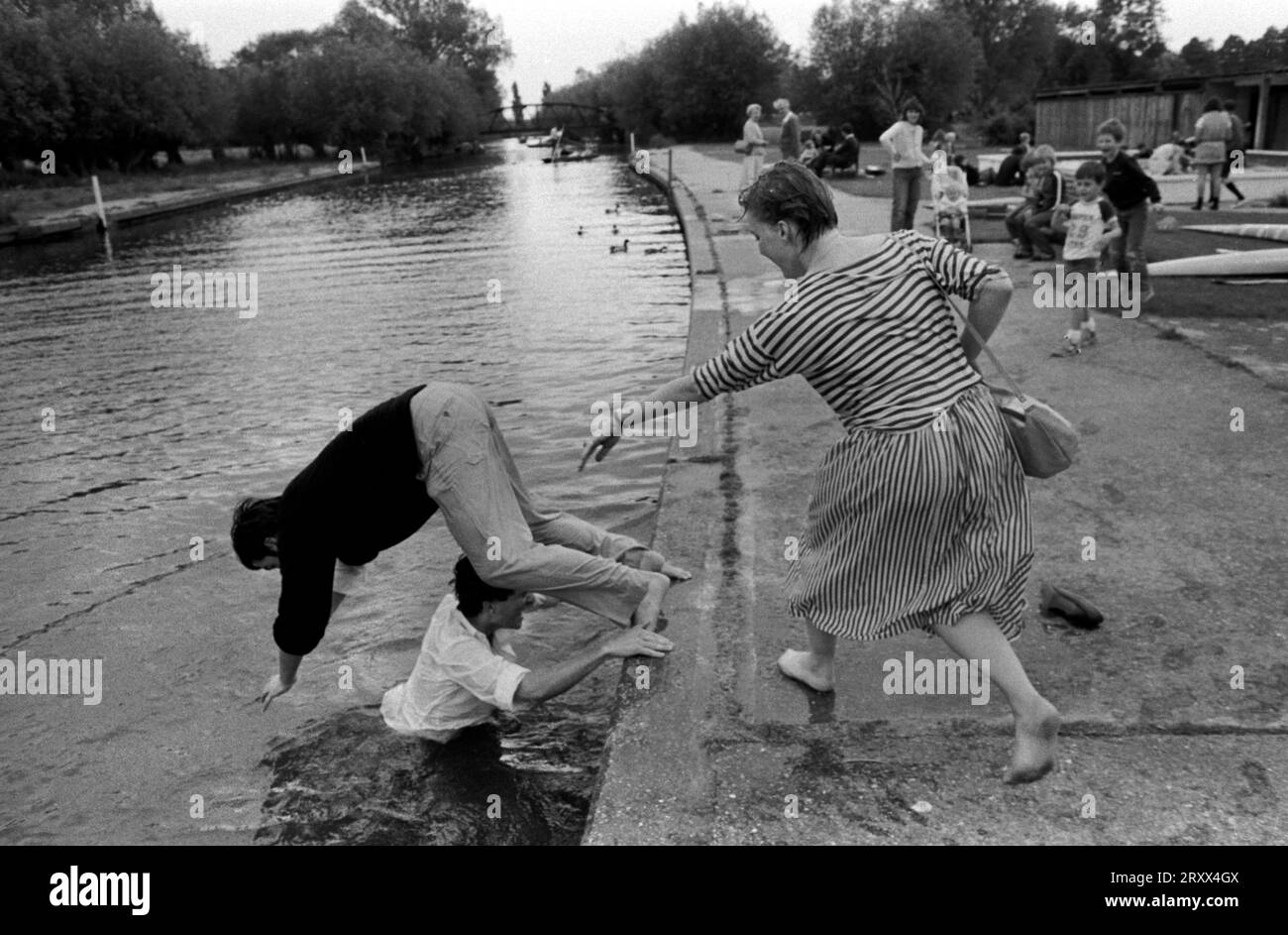 Betrunkene Studenten mit Spaß Cambridge 1980s UK. Studentin, die einen männlichen Universitätsstudenten in den Fluss Cam schiebt. Cambridge, Cambridgeshire 1983 1980er Jahre UK HOMER SYKES Stockfoto