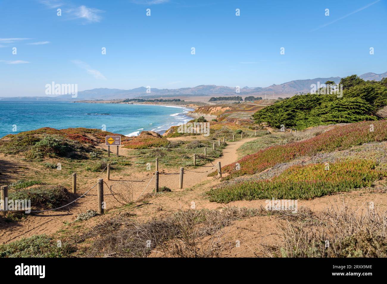 Verlassener Pfad auf der Spitze der Klippe entlang der Küste von Zentral-Califronia an einem klaren Herbsttag. Kalifornien State Route eins in der Entfernung sichtbar. Stockfoto