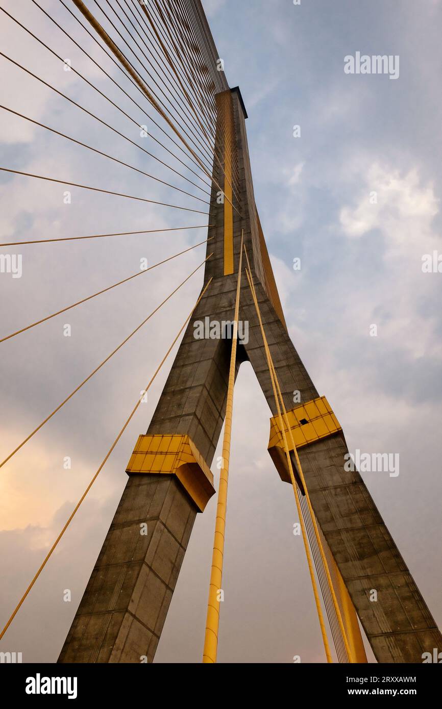 Eine hoch aufragende Hängebrücke mit Betonsäulen und Stahlseilen steht vor einem bewölkten Himmel. Stockfoto