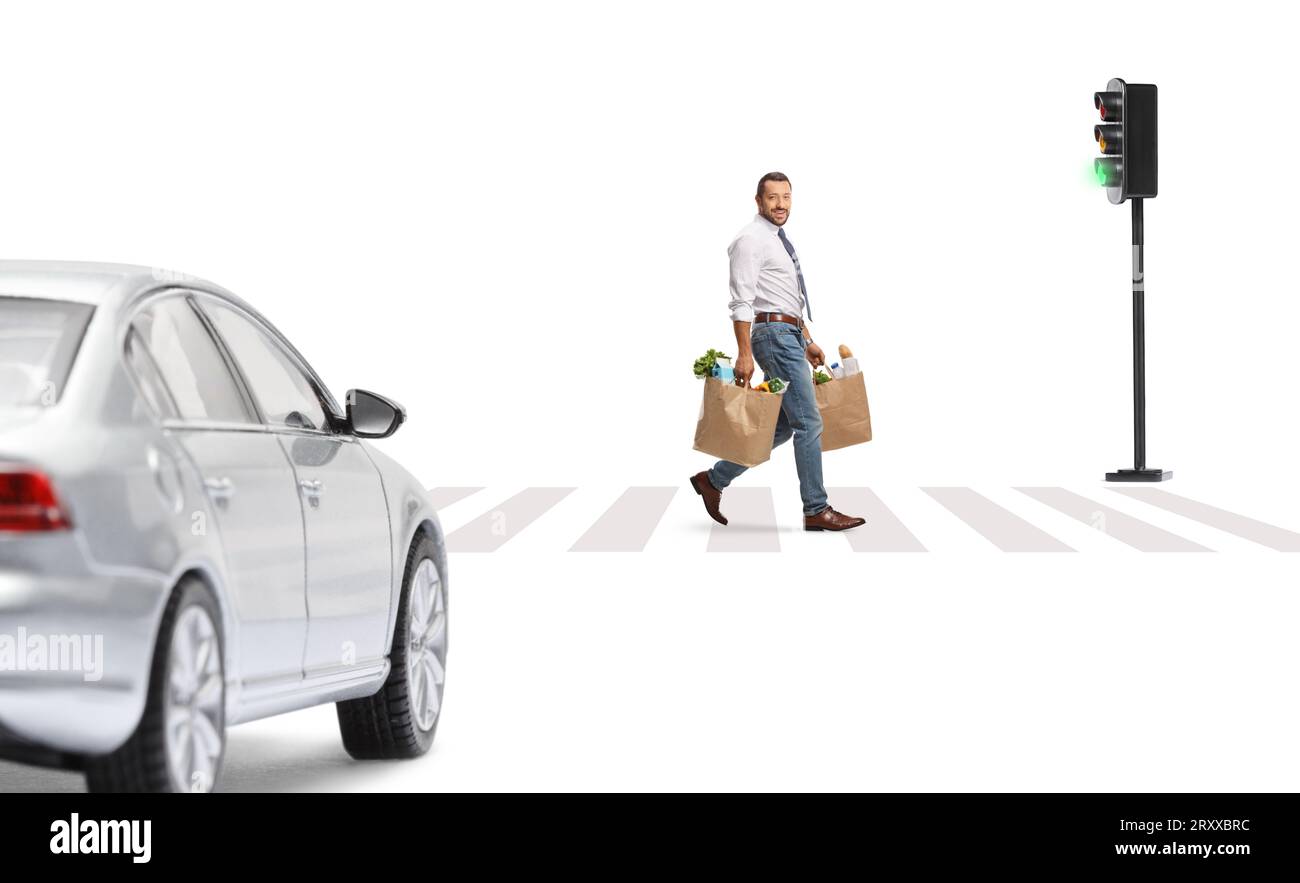 Geschäftsmann mit Lebensmitteltaschen, die eine Straße an einer grünen Ampel überqueren, isoliert auf weißem Hintergrund Stockfoto