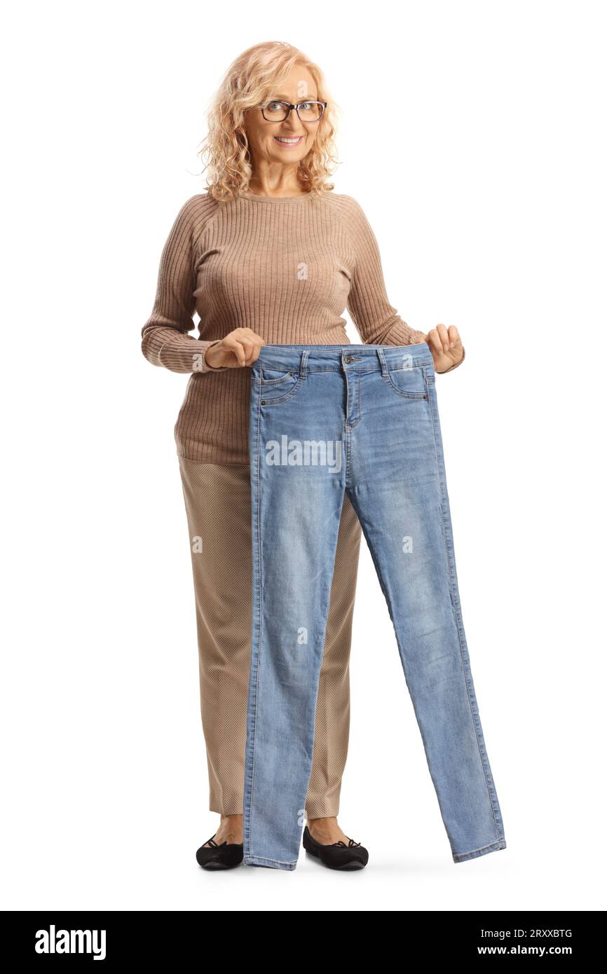 Reife Frau, die eine Jeans hält und die Kamera isoliert auf weißem Rücken betrachtet Stockfoto
