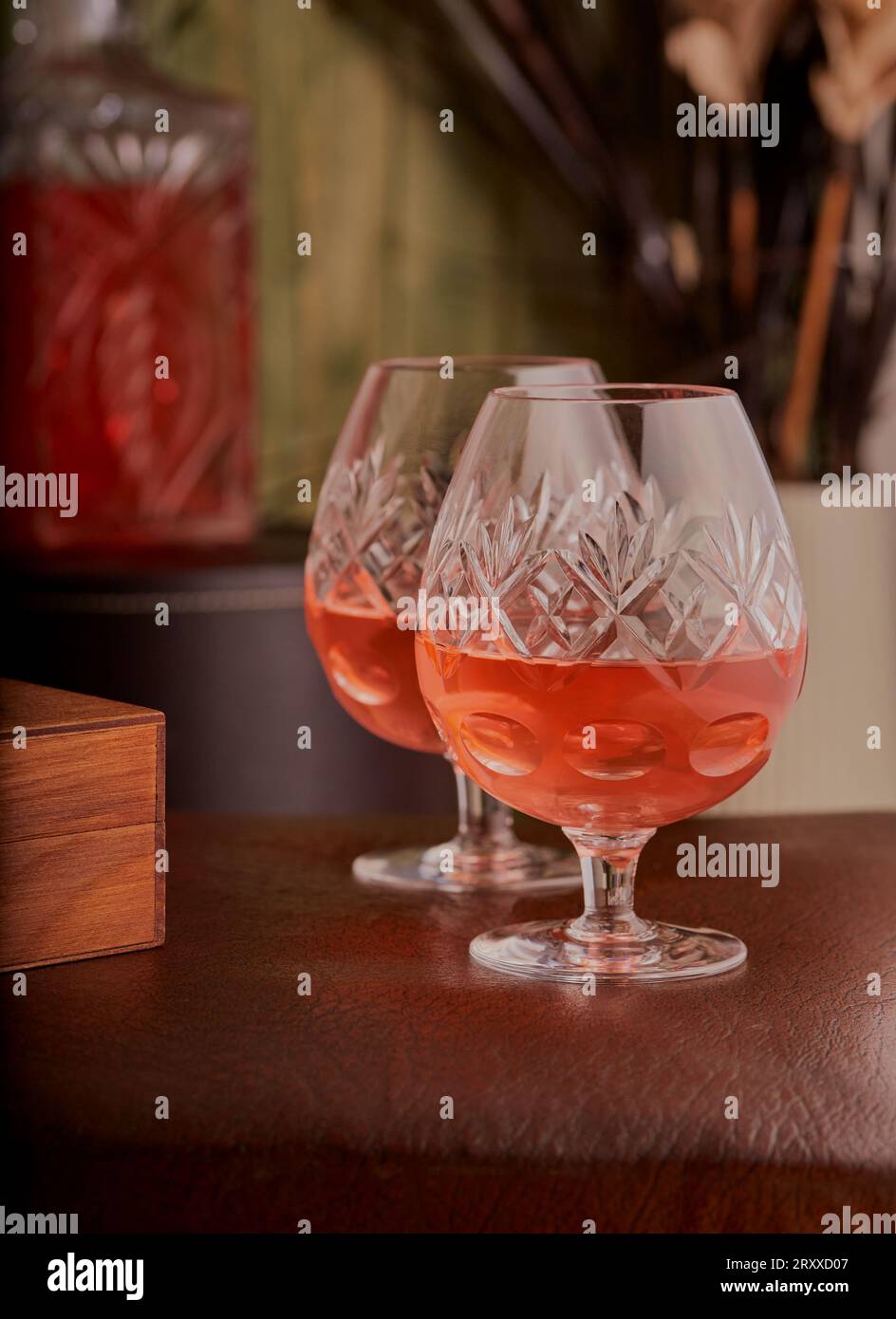Eine luxuriöse Brandy-Brille mit Brandy im Inneren und einer Brandy-Karaffe im Hintergrund. Stockfoto