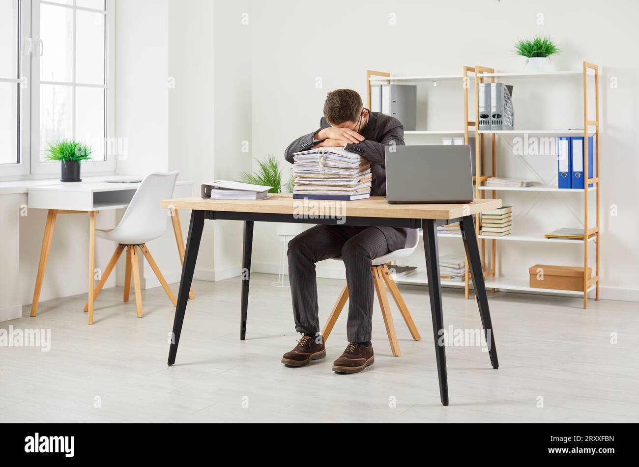Erschöpfter Mitarbeiter, der es satt hat, zu viel zu arbeiten, schläft auf Stapeln von Ordnern mit Dokumenten im Büro. Stockfoto