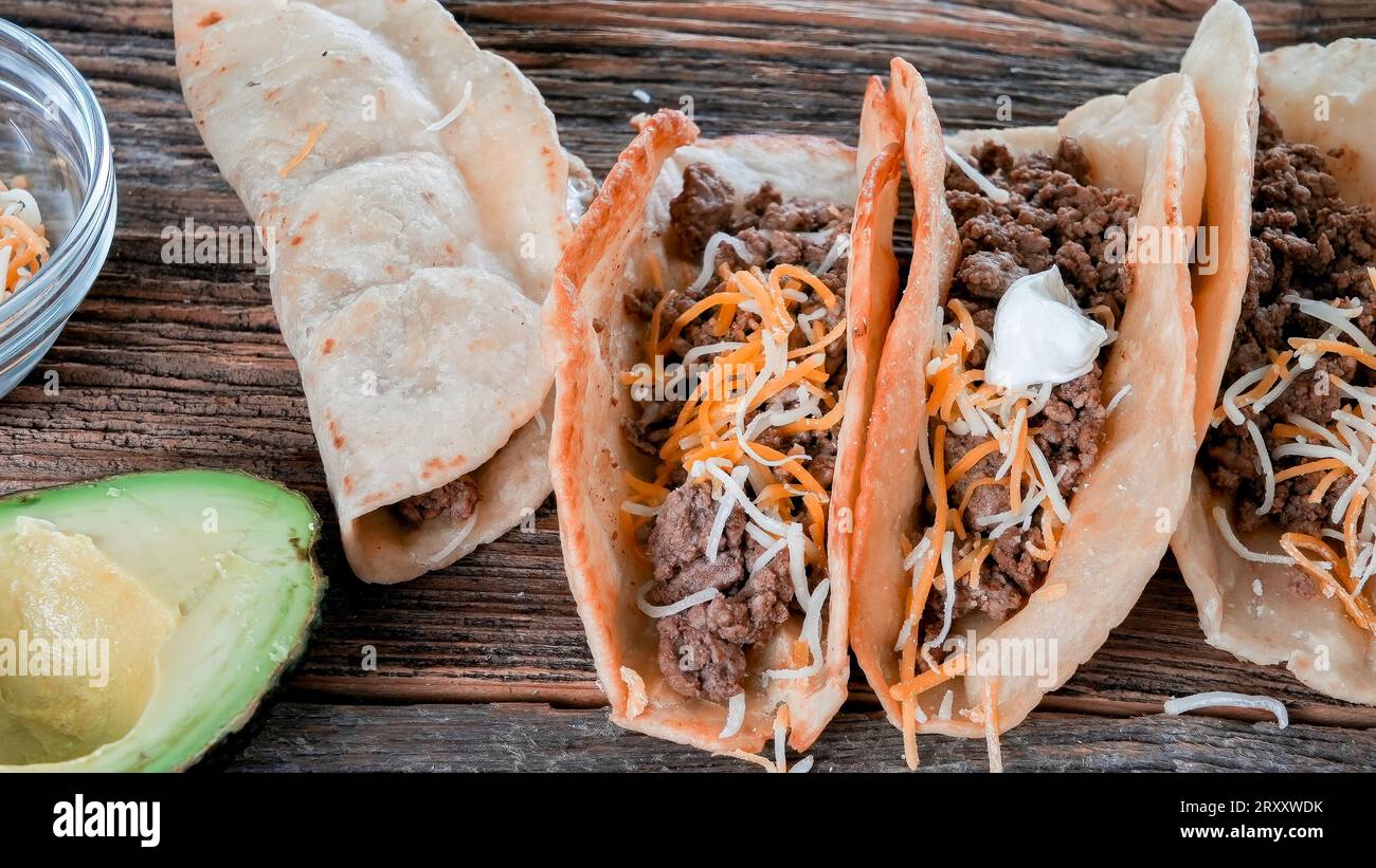 Gemahlene Rindfleisch-Tacos auf rustikalem Holztisch Stockfoto