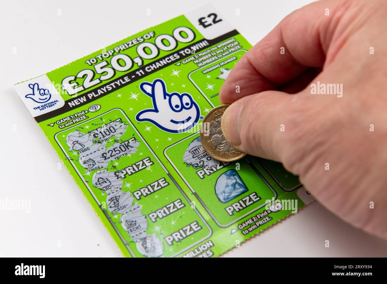 London. UK- 09.27.2023. Eine nationale Lotterie-Rubbelkarten, die in weiß isoliert sind, wobei ein Spieler eine Münze verwendet, um die Karte zu zerkratzen. Stockfoto