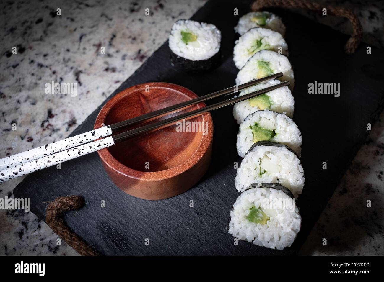Hausgemachtes vegetarisches Sushi-Gericht mit Seetang, Reis, Gurke, Avocado und veganem Käse. Daneben ein Holzbehälter für Sojasauce und wiederverwendbare Meta Stockfoto