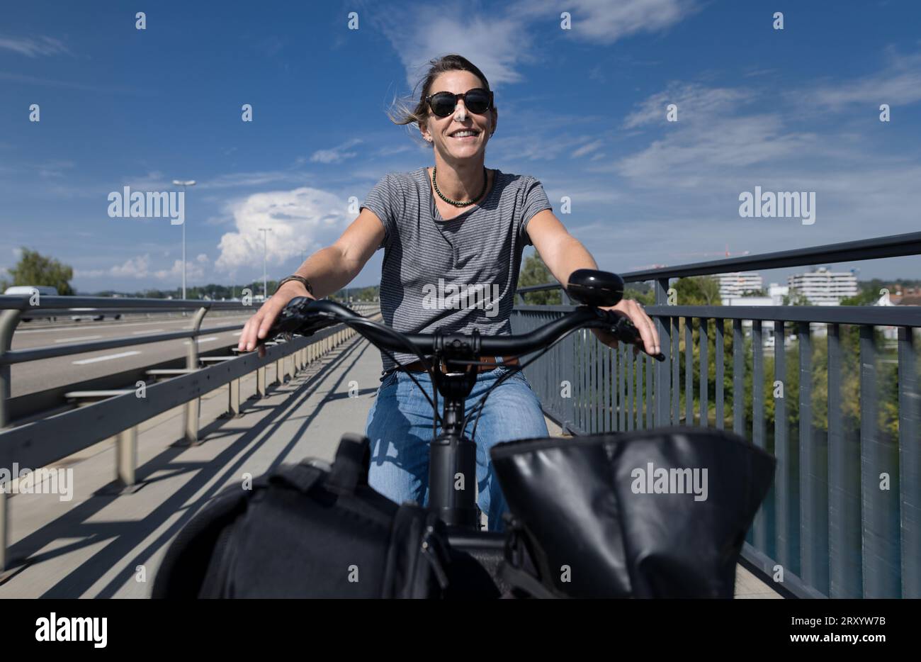 Frau mit Elektro-Lastenrad Fahrrad mit Taschen und Gepäck auf Radweg mit Lastenrad Fahrrad Fahrrad Stockfoto