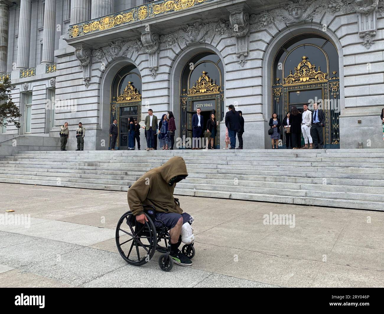 26. August 2023, San Francisco, Kalifornien, USA: Ein Obdachloser im Rollstuhl fährt am Samstag, den 26. August 2023, an der San Francisco City Hall in San Francisco, Kalifornien vorbei. Die beworbene â€˜Doom Loop Tourâ€™ war eine No-Show und sollte im Rathaus beginnen und verschiedene heruntergekommene Bereiche der Innenstadt von San Francisco abdecken. (Bild: © David G. McIntyre/ZUMA Press Wire) NUR REDAKTIONELLE VERWENDUNG! Nicht für kommerzielle ZWECKE! Stockfoto