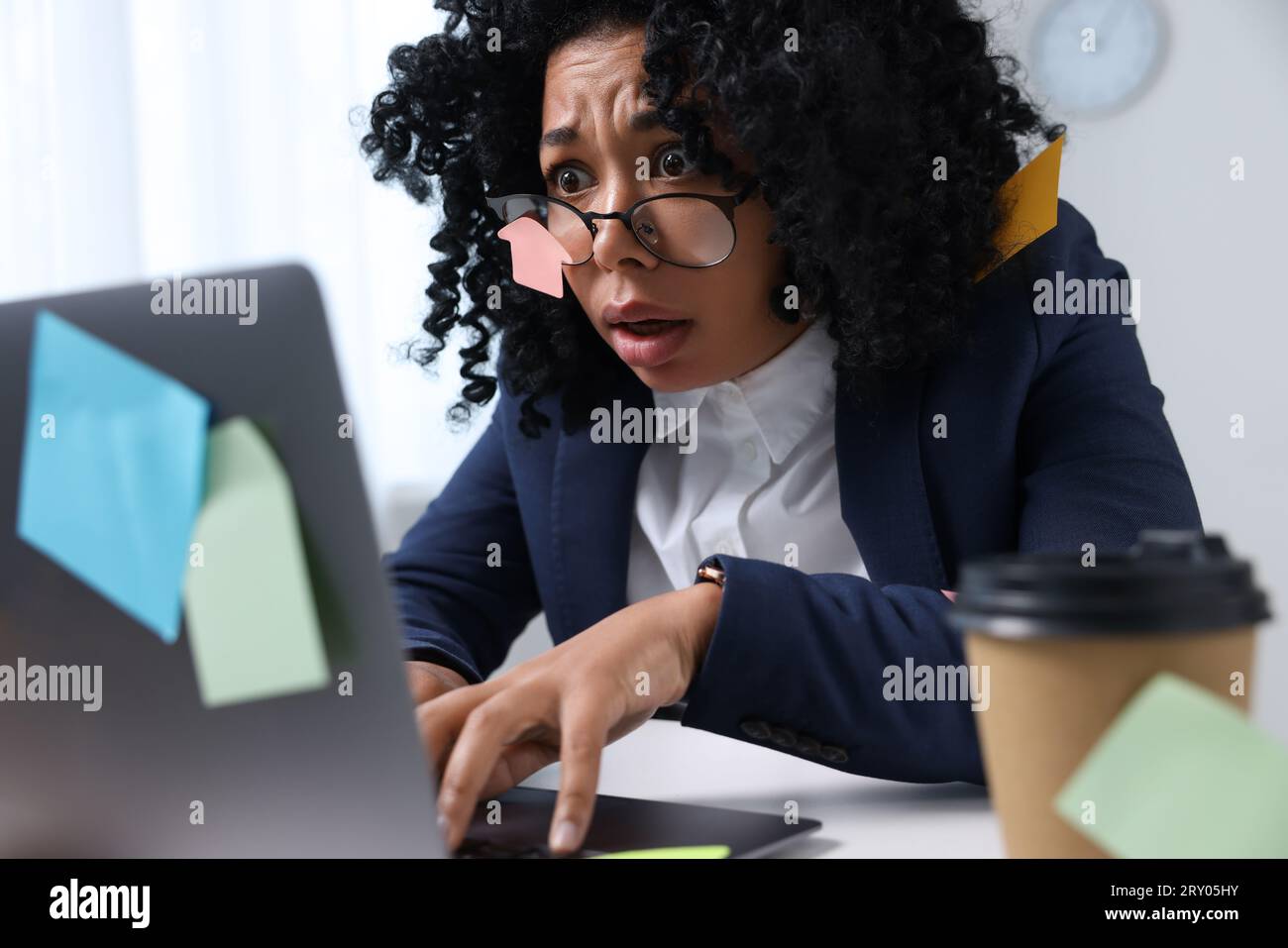 Terminkonzept. Gestresste Frau, die auf dem Laptop schreibt. Viele Haftnotizen überall als Erinnerung Stockfoto