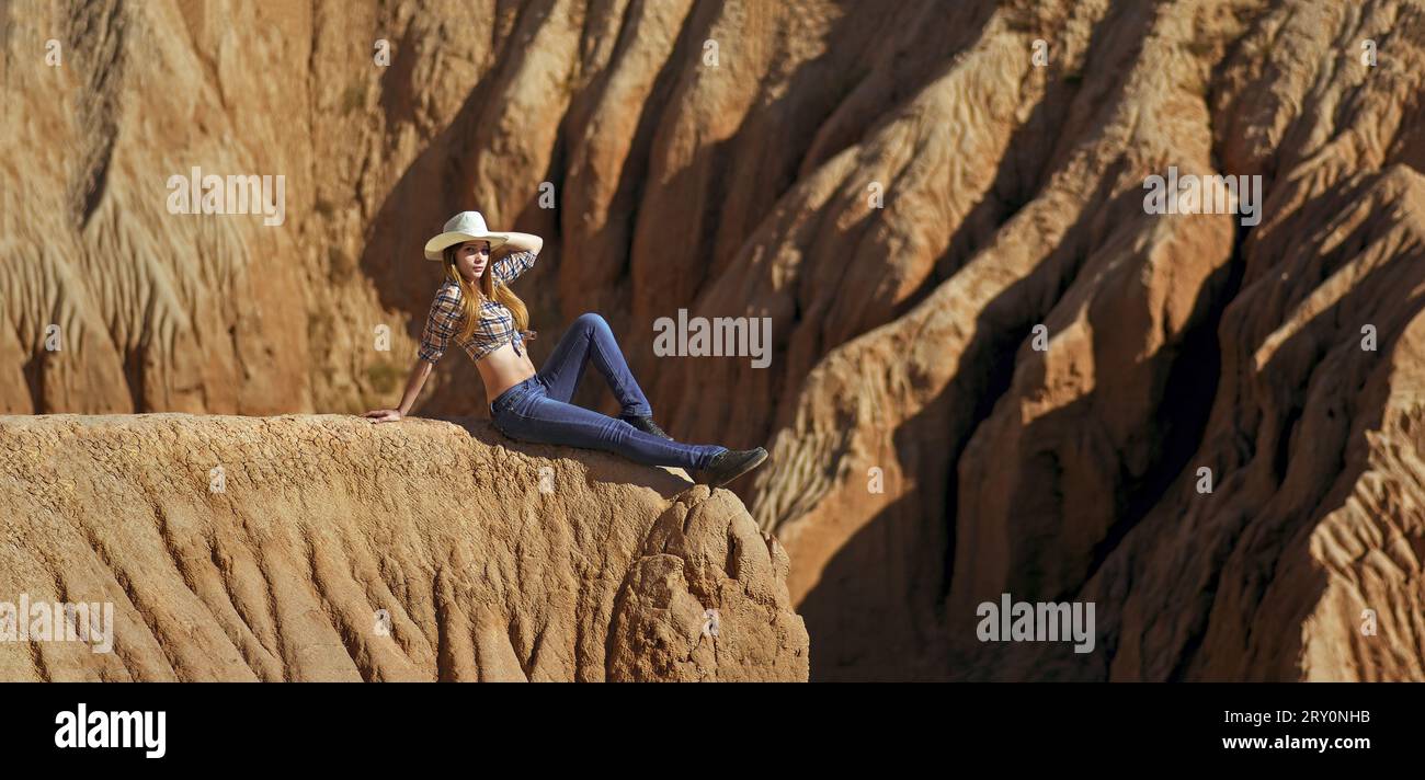 Junge, schöne Frau in Cowboykleidung, sitzt am Rande des Grand Canyon. Stockfoto