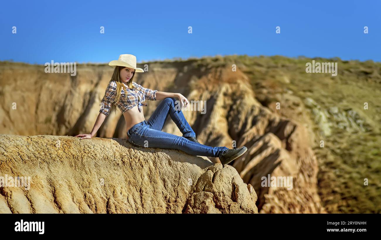 Junge, schöne Frau in Cowboykleidung, sitzt am Rande des Grand Canyon. Stockfoto