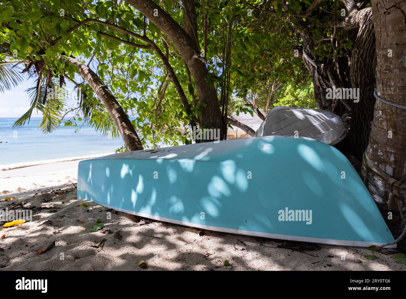 Blaues Boot lag kopfüber im Schatten am Strand Stockfoto