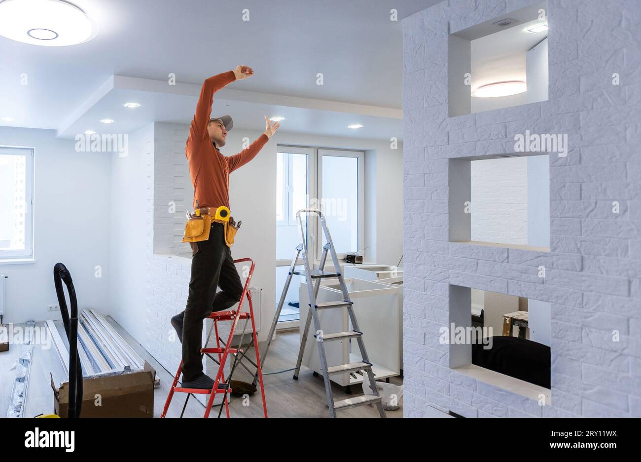 Elektriker repariert Deckenventilator mit Lampen im Innenbereich. Platz für Text. Stockfoto