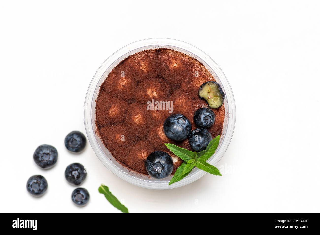 Traditionelles italienisches süßes Dessert aus Tiramisu-Kuchen im Glas auf weißem Hintergrund. Mit einer erfrischenden, gesunden Zugabe von großen, saftigen Heidelbeeren. Flach Stockfoto