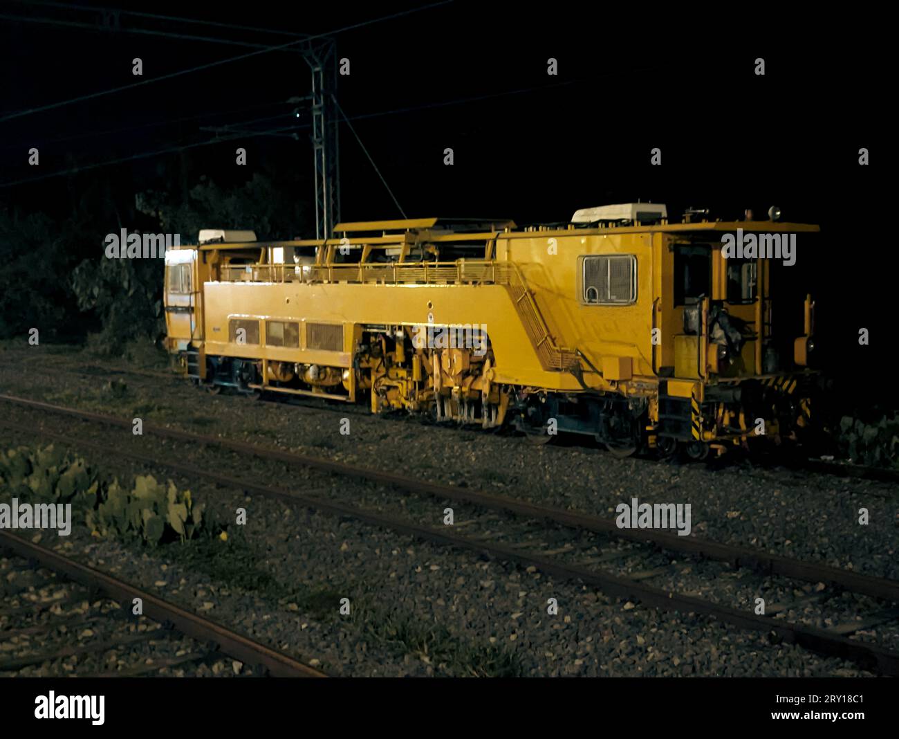 Ein alter alter gelber Lokomotiven-Dieselmotor eines Zuges auf dem Gleis in der Nähe eines Bahnhofs bei Nacht Stockfoto