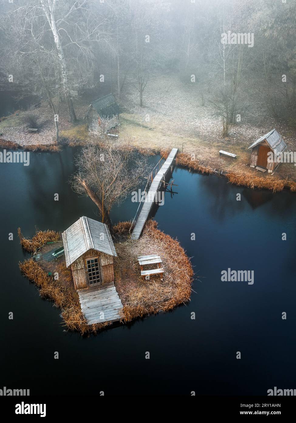 Szodliget, Ungarn - Luftaufnahme einer traumhaften Winterszene am Szodliget Angelsee mit kleiner Insel, Fischerhütten und starkem Nebel in einem kalten Winter mehr Stockfoto