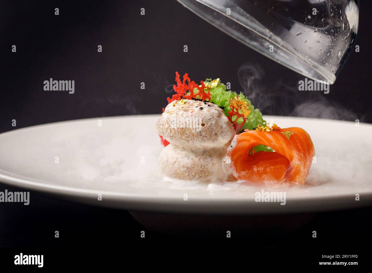 Molekulare moderne Küche Gravlaxforelle mit Knoblaucheis auf schwarzem Hintergrund. Stockfoto