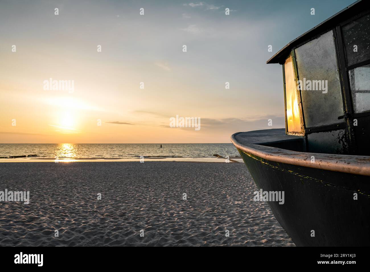Sonnenuntergang am Strand an der polnischen Ostsee. Fischerboot am Abend in der Nähe von Międzyzdroje, Polen. Stockfoto