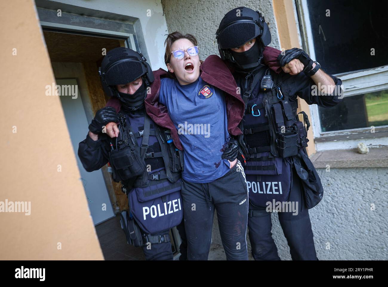 28. September 2023, Sachsen, Wiederau: Offiziere der Einheit Lebel (lebensbedrohliche Einsatzsituationen) retten eine verletzte Frau aus einer Kaserne während einer Terrorübung. Rund 150 Auszubildende des Deutschen Roten Kreuzes, Samariter und Johanniter aus Sachsen und Sachsen-Anhalt nehmen am Ende einer Trainingswoche an einer inszenierten Terrorsituation Teil. Es gab einen Angriff mit zahlreichen Opfern: Der Täter hat sich verwurzelt, Schüsse werden abgefeuert, es gibt Rauch, schwer bewaffnete und verhüllte Polizisten stürmen das Gebäude. Danach müssen die Rettungssanitäter das i behandeln Stockfoto