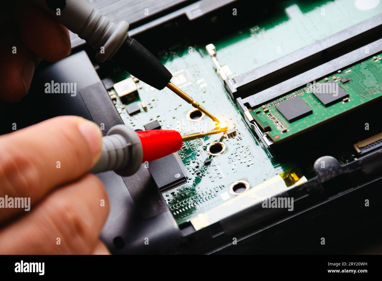 Elektriker prüft die elektronische Leiterplatte mit der Prüfspitze des Digitalmultimeters. Techniker prüft und diagnostiziert Probleme mit PC-Mainboards. Anwendung Stockfoto