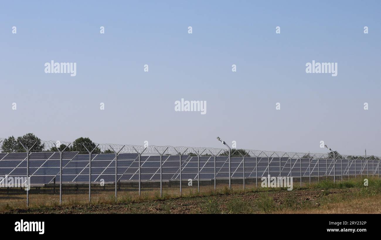 Ein Komplex von Solarpaneelen, die auf einem Landfeld hinter einem Drahtzaun stehen, Solarpaneele in Betrieb sind, moderne Geräte im Energiebereich Stockfoto