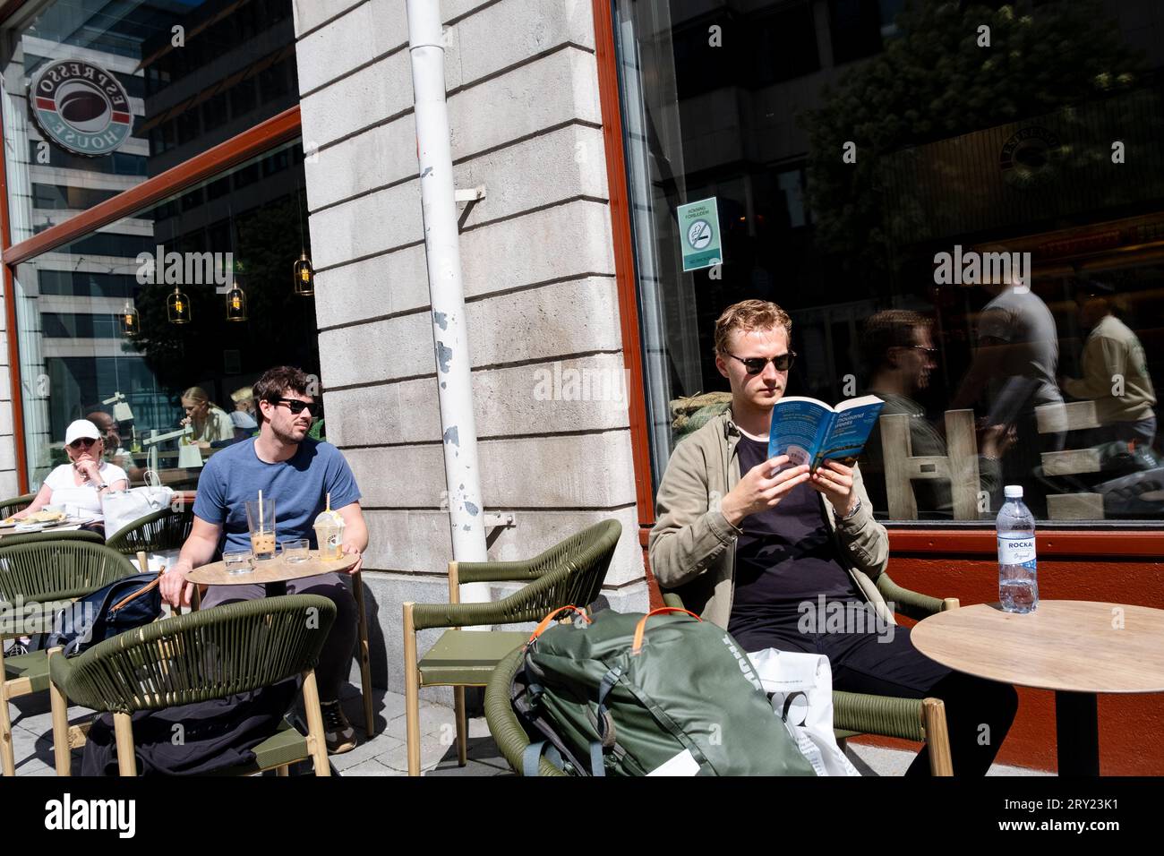 Ein Mann liest viertausend Wochen von Oliver Burkeman, der draußen in einem Café in Stockholm sitzt. Foto: Rob Watkins Stockfoto