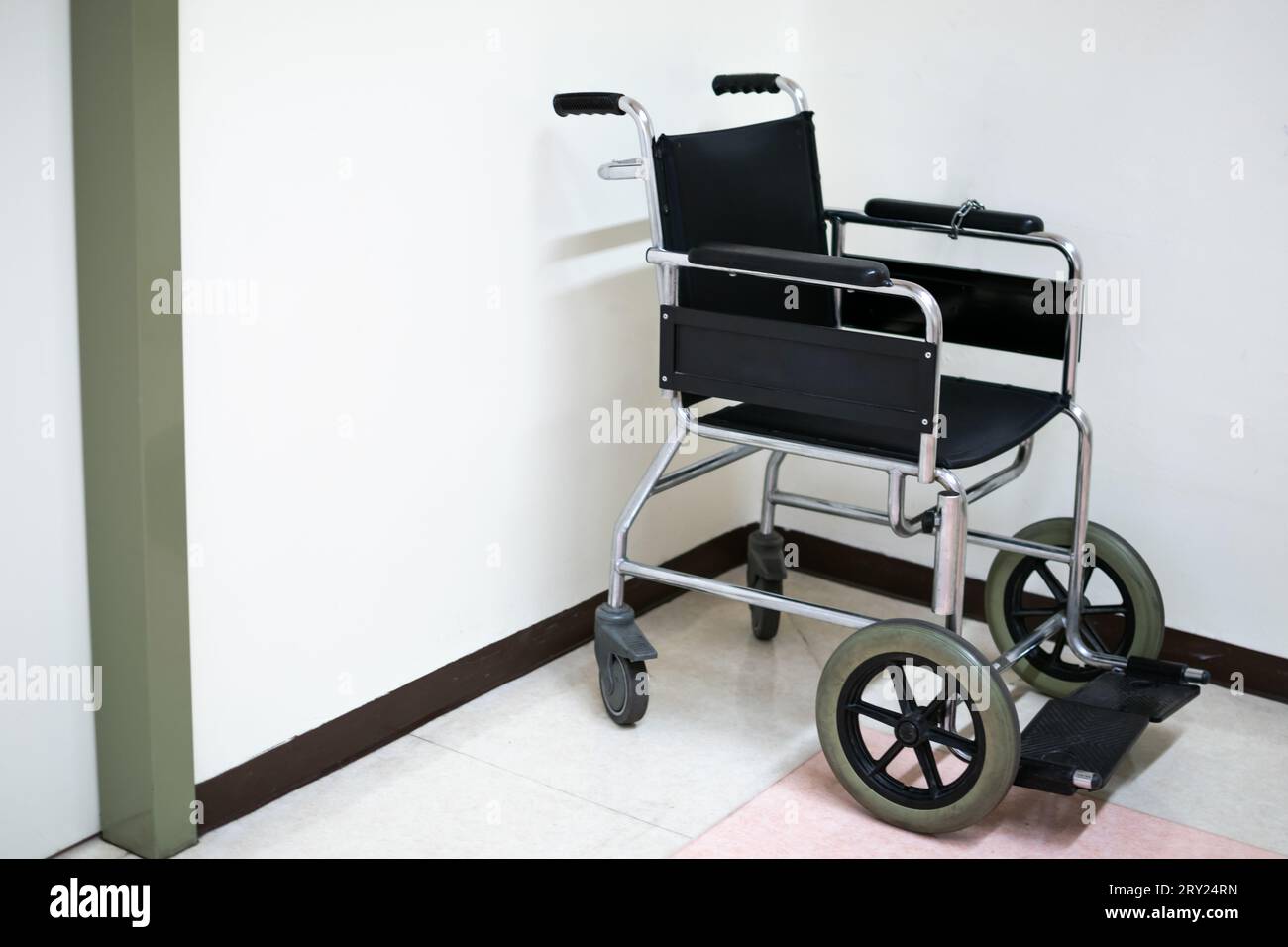 Schwarzer Rollstuhl auf Krankenhausboden mit weißem Hintergrund Stockfoto