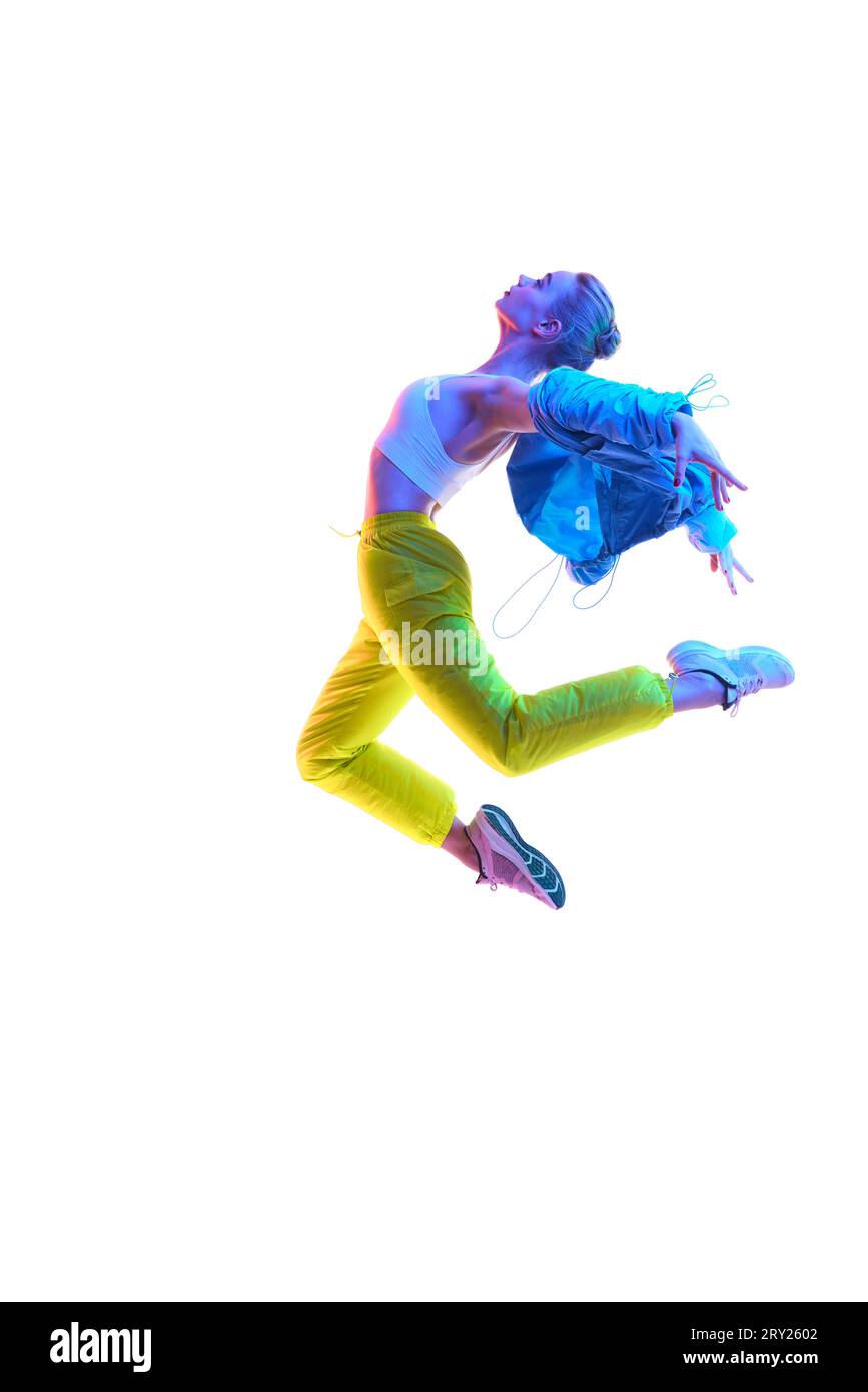 Attraktive angeregte Fitness-Mädchen-Tänzerin in Sportbekleidung tanzen in Neonlicht in Luft isoliert über weißem Hintergrund. Stockfoto