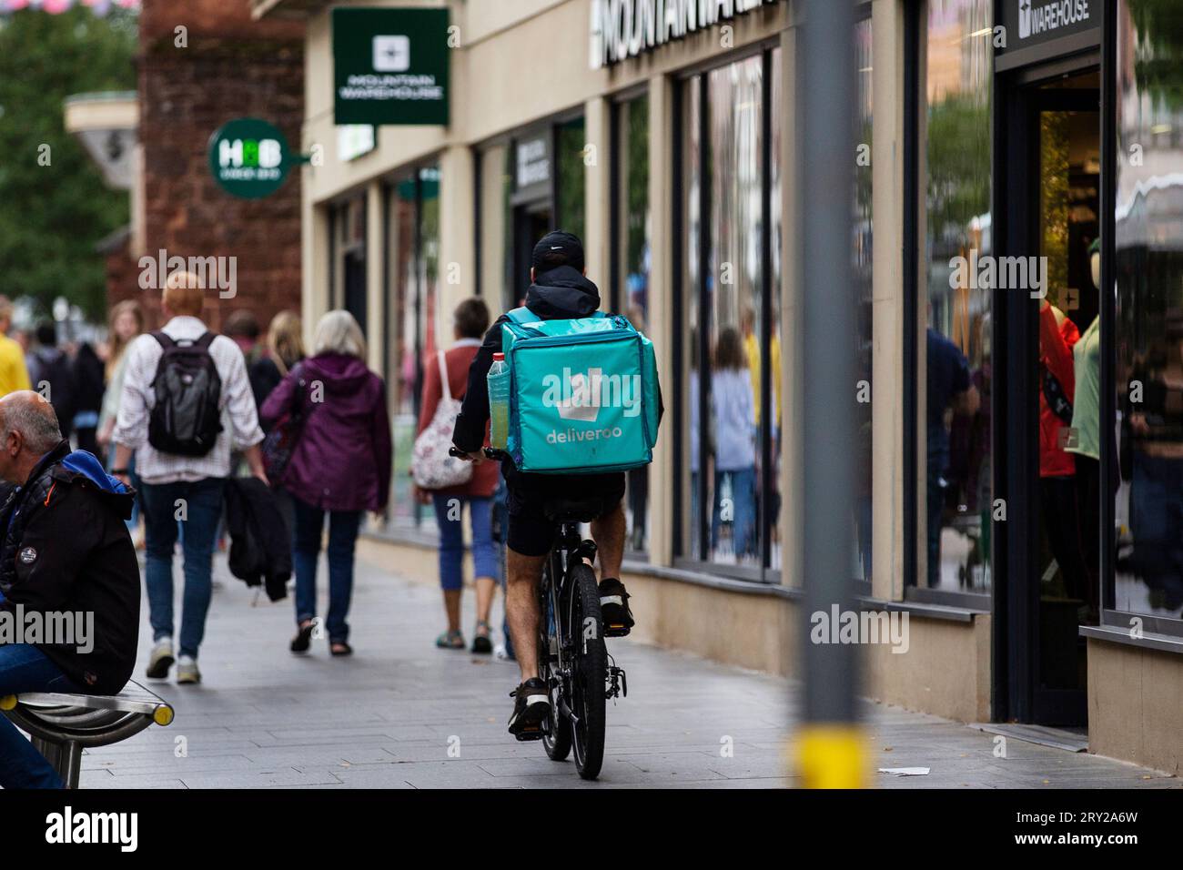 Lieferradler im Einkaufszentrum Exeter City, während tagsüber viel los ist - Deliveroo Stockfoto