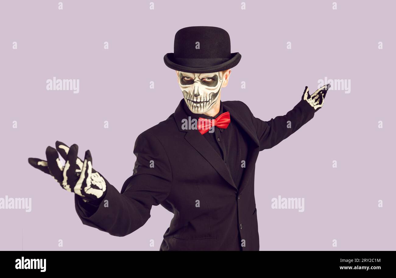 Der Mann im Skelett-Kostüm begrüßt dich mit einer Geste und lädt dich zu einer Halloween-Party ein Stockfoto