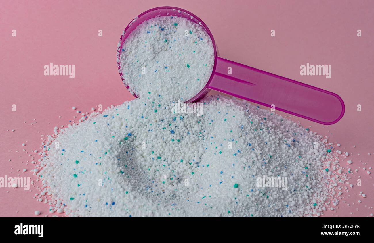 Waschpulver in Plastiklöffel auf rosafarbenem Hintergrund, Draufsicht. Hochwertige Fotos Stockfoto