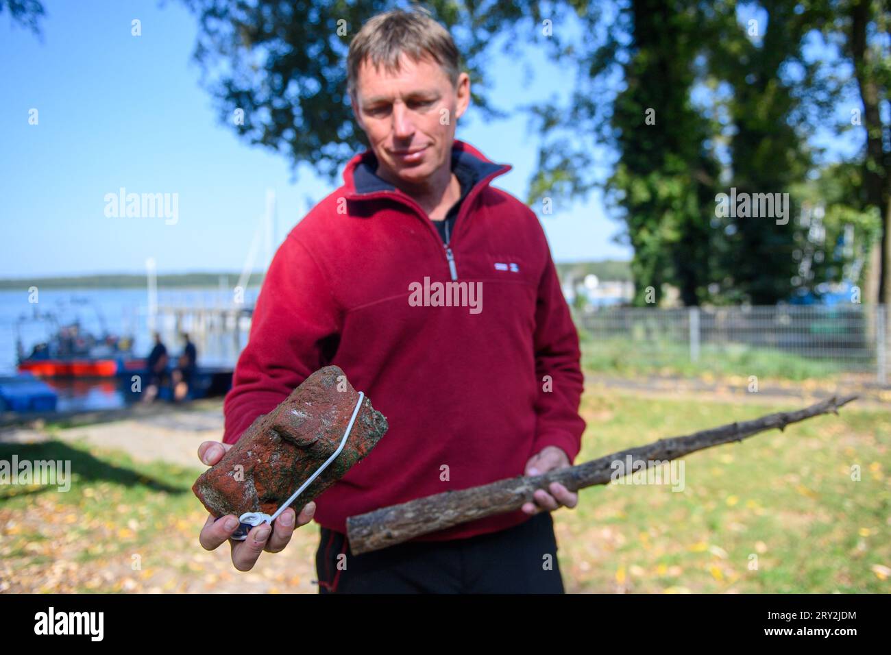 28. September 2023, Sachsen-Anhalt, Arendsee: Sven Thomas, Unterwasserarchäologe des Landesamtes für Denkmalpflege und Archäologie Sachsen-Anhalt zeigt zwei Funde vom Arendsee, einen Stein aus dem Kloster und einen Teil eines Zauns. Die Archäologen untersuchen seit dem 25. September 2023 Stätten am Fuße des Lake Arend. Bis Ende der Woche sollen insgesamt 20 Ziele in hoher Auflösung und in 3D befragt werden. Unter anderem wurden Fischzäune verschiedener Epochen entdeckt. Fraunhofer-Institut für Optronik, Systemtechnik und Bildausnutzung Stockfoto