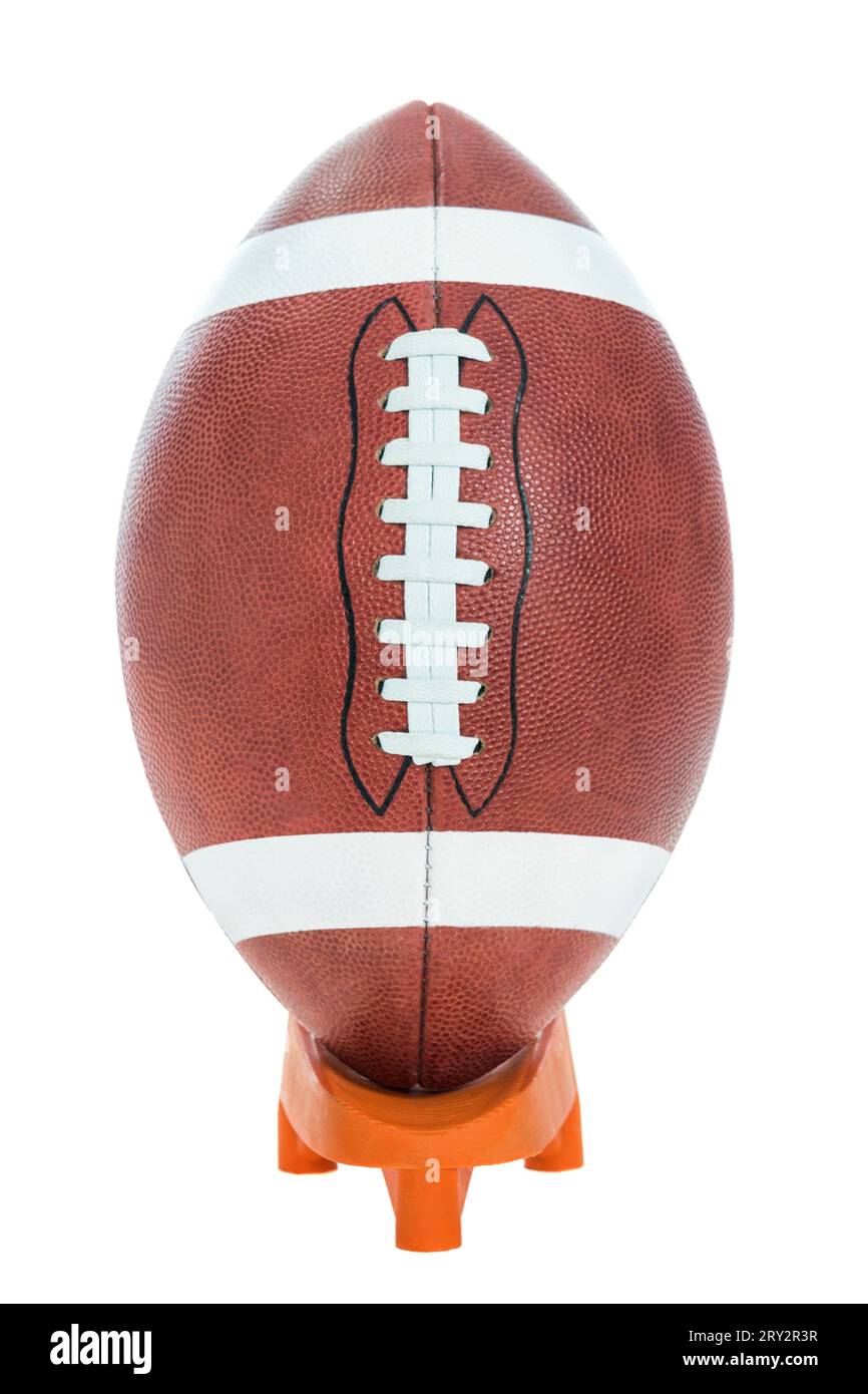 Eine Nahaufnahme eines American Football mit weißem Streifen, der für College- und Highschool-Fußballspiele verwendet wird, auf einem orangen T-Stück auf weißem Hintergrund. Stockfoto