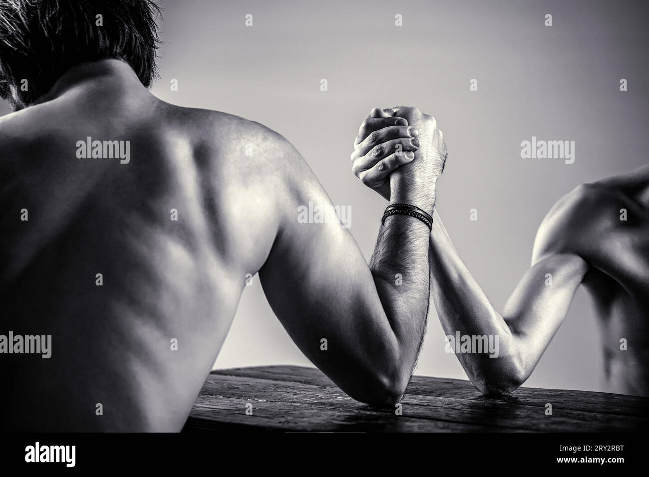 Arme, die dünne Hand wringen, großer, starker Arm. Zwei Männer haben Armringen geschlossen, stark und schwach, ungleiche Übereinstimmung. Schwarz-weiß Stockfoto