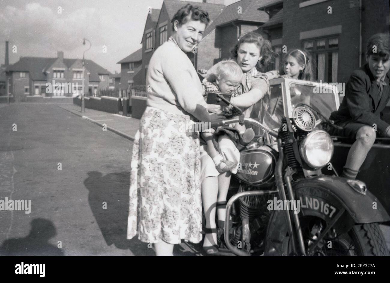 1960er Jahre, historisch, draußen in einer Vorstadtstraße, zwei Damen und Kinder neben und auf einem Harley Davidson Motorrad und Beiwagen der Ära, Oldham, England, Großbritannien. Stockfoto