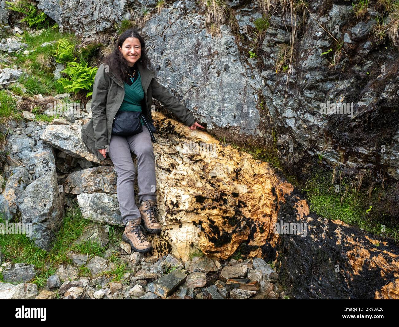Lächelnde Frau, die auf den Moine Thrust zeigt, North West Highlands Geopark, Knockan Crag, Schottland Stockfoto