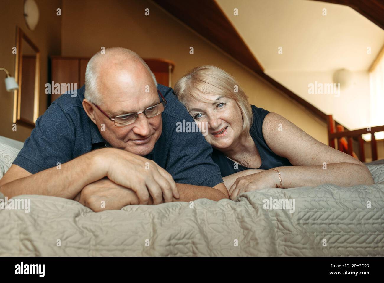 Porträt eines verheirateten älteren Ehepaares, das auf dem Bett liegt. Stockfoto