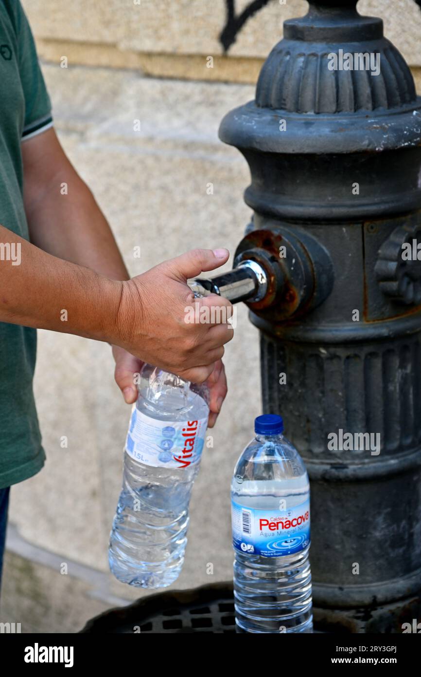 Man füllt Wasserflaschen am alten traditionellen öffentlichen Trinkwasserbrunnen Stockfoto