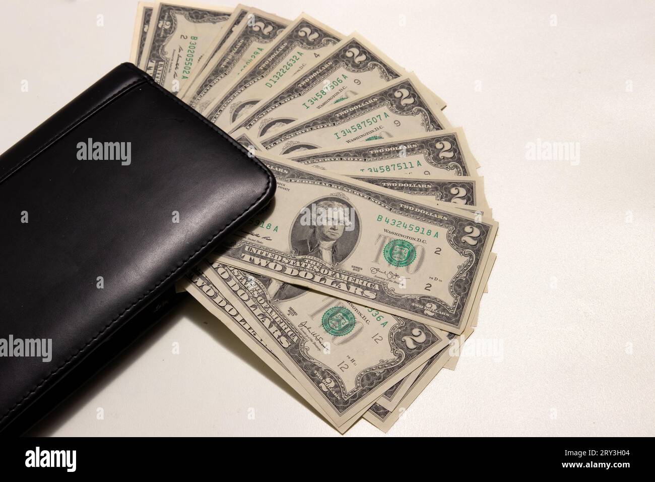 Foto von zwei Dollarscheinen auf weißem Hintergrund mit Kopierraum neben einer Brieftasche. Stockfoto