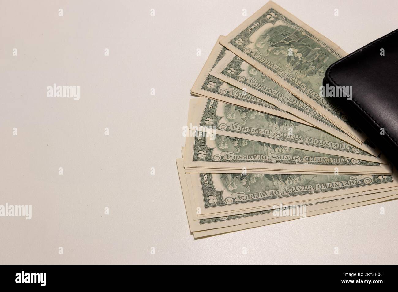 Foto von zwei Dollarscheinen auf weißem Hintergrund mit Kopierraum neben einer Brieftasche. Stockfoto